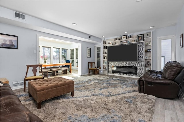 living room with recessed lighting, visible vents, baseboards, and wood finished floors