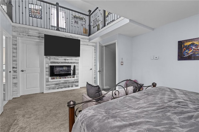 carpeted bedroom with a fireplace and a towering ceiling