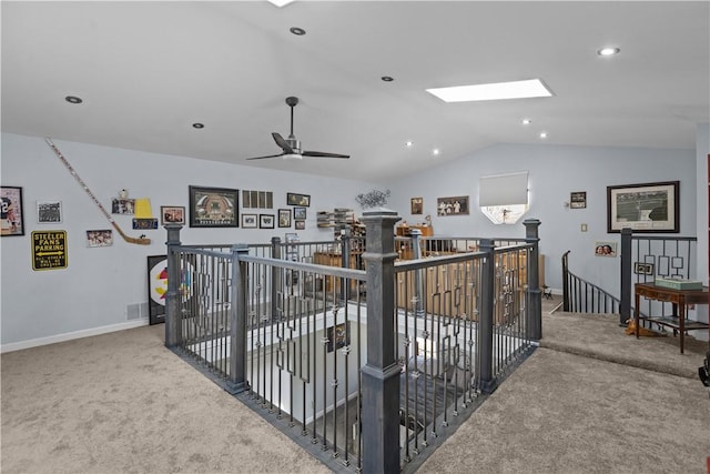 interior space with carpet floors, baseboards, an upstairs landing, and lofted ceiling with skylight