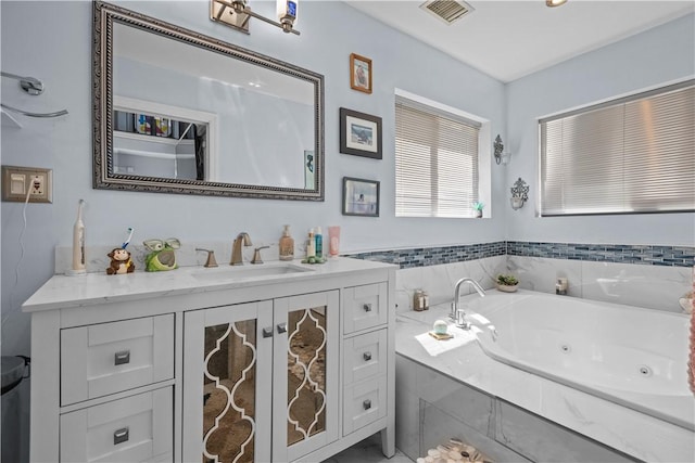 bathroom featuring vanity, a tub with jets, and visible vents