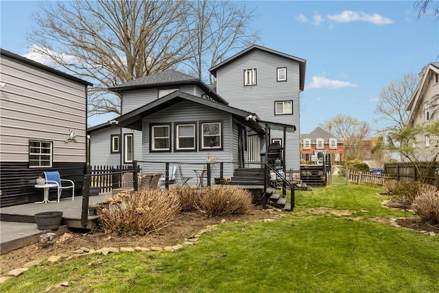 rear view of house featuring a wooden deck, fence, and a lawn