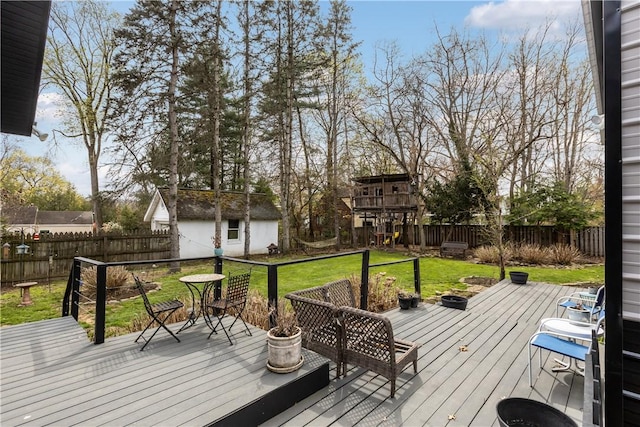 wooden deck featuring an outbuilding, a fenced backyard, and a lawn