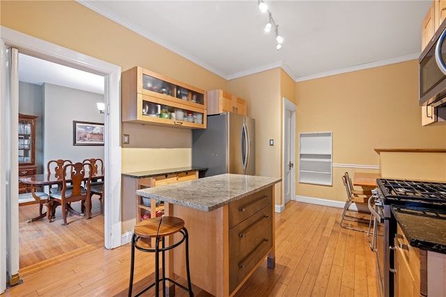 6429 Bartlett St, Squirrel Hill, PA 15217 - kitchen featuring light wood-type flooring, glass insert cabinets, a center island, a kitchen bar, and appliances with stainless steel finishes