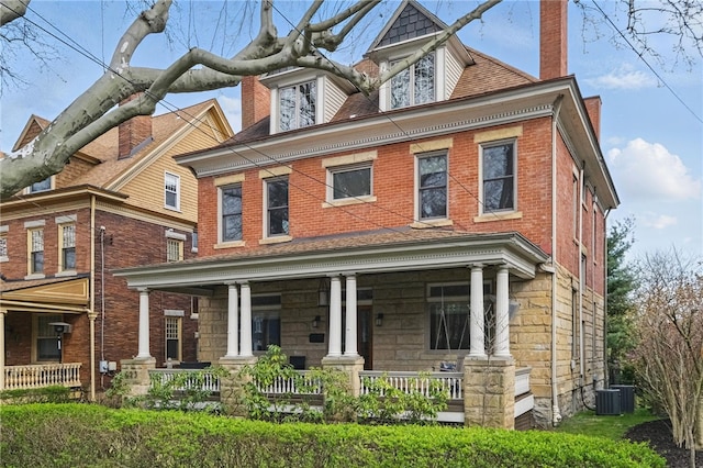 view of front facade with central AC unit, covered porch, and a chimney