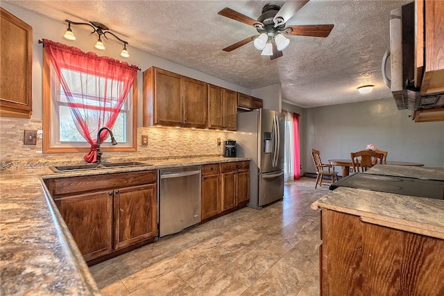 kitchen featuring tasteful backsplash, a ceiling fan, a sink, stainless steel appliances, and brown cabinets
