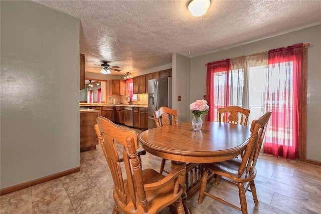 dining area with a textured ceiling, baseboards, and a ceiling fan