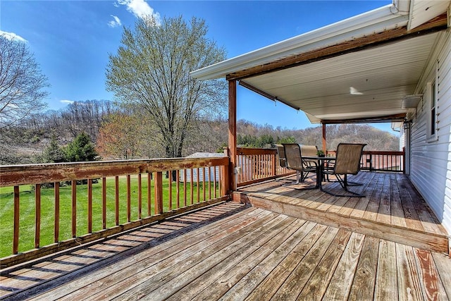 wooden terrace with outdoor dining area and a lawn