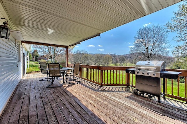 wooden deck with area for grilling, a yard, and outdoor dining area