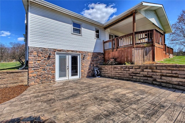 rear view of property featuring a deck and stone siding