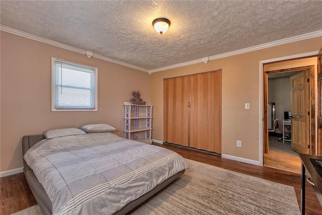 bedroom featuring a closet, baseboards, wood finished floors, and a textured ceiling