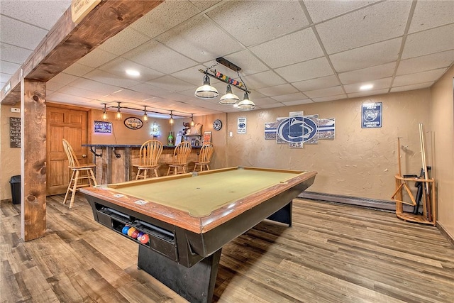 playroom with indoor bar, a textured wall, a baseboard heating unit, and wood finished floors