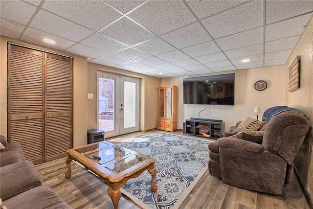 living room with french doors, recessed lighting, a paneled ceiling, and wood finished floors