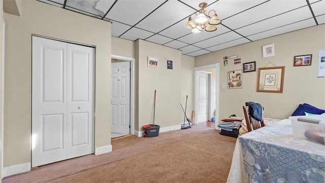 carpeted bedroom featuring a paneled ceiling, a closet, and baseboards