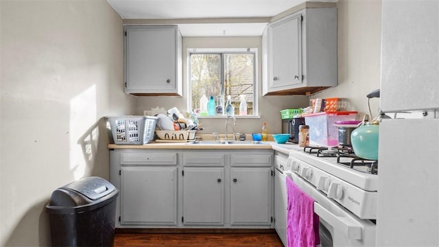 kitchen with dark wood-style floors, light countertops, a sink, and white gas range oven