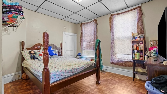bedroom with a paneled ceiling and baseboards