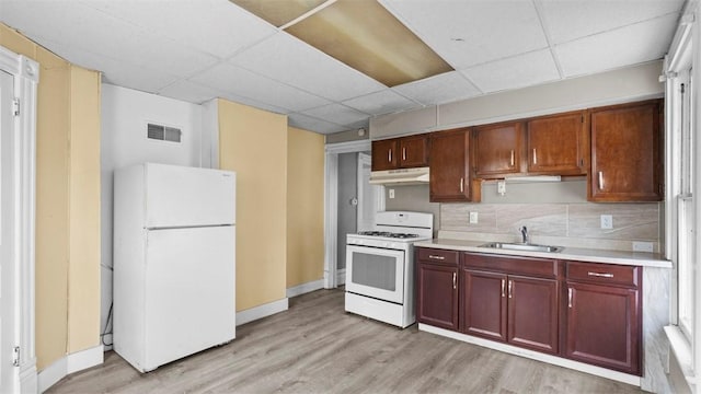 kitchen featuring under cabinet range hood, white appliances, a paneled ceiling, and a sink