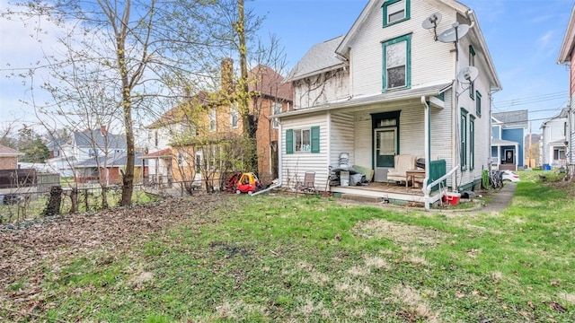 rear view of property with a yard and fence