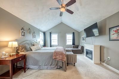 bedroom with baseboards, a ceiling fan, carpet flooring, a glass covered fireplace, and lofted ceiling