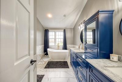 full bath with marble finish floor, a soaking tub, a healthy amount of sunlight, and vanity