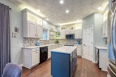 kitchen with dark wood finished floors, a center island, light countertops, stainless steel appliances, and decorative backsplash
