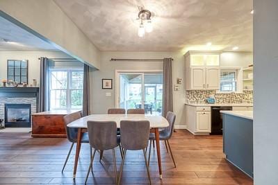 dining area featuring wood-type flooring and a glass covered fireplace