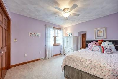 bedroom with ceiling fan, light colored carpet, and baseboards