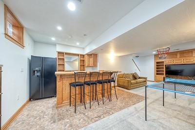 bar with a bar, baseboards, recessed lighting, and black fridge with ice dispenser