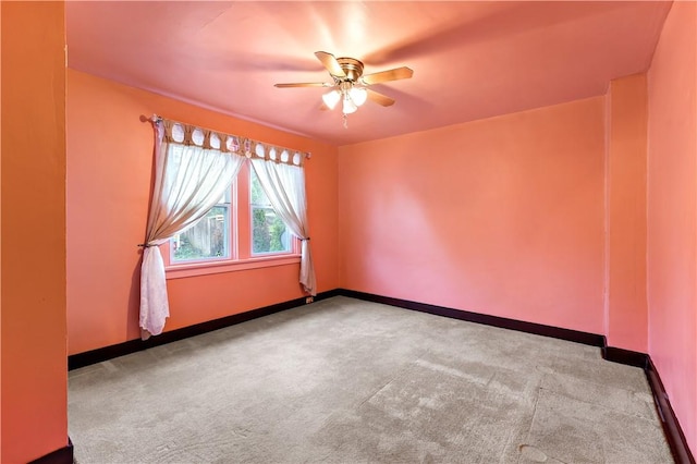 carpeted empty room featuring baseboards and a ceiling fan