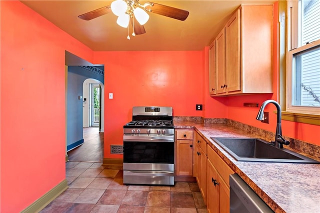 kitchen with baseboards, arched walkways, a sink, ceiling fan, and appliances with stainless steel finishes