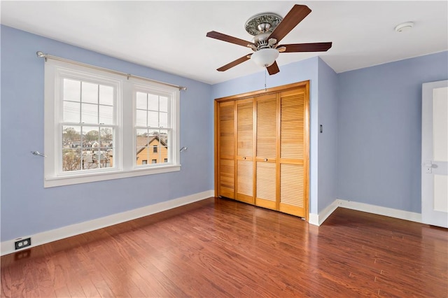 unfurnished bedroom with a closet, baseboards, a ceiling fan, and wood finished floors