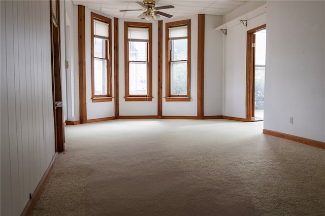 spare room featuring light carpet, a wealth of natural light, baseboards, and ceiling fan