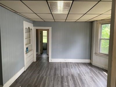 140 Washington Ave, Bellevue, PA 15202 - spare room with wooden walls, baseboards, a drop ceiling, and wood finished floors