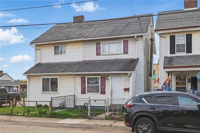 townhome / multi-family property featuring roof with shingles, a chimney, a fenced front yard, and a gate
