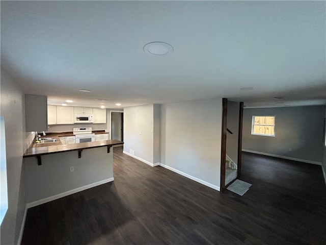 kitchen featuring open floor plan, white appliances, a sink, and dark wood finished floors