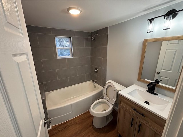 bathroom featuring toilet, wood finished floors, vanity, and shower / washtub combination