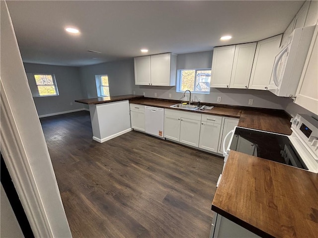 kitchen with wood counters, recessed lighting, white appliances, and a sink