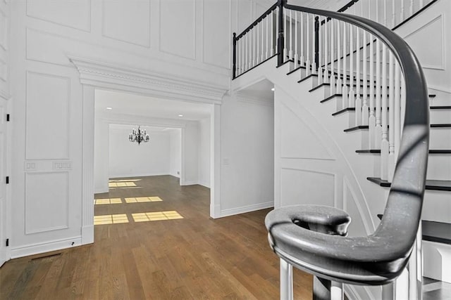 foyer featuring crown molding, baseboards, wood finished floors, and stairway