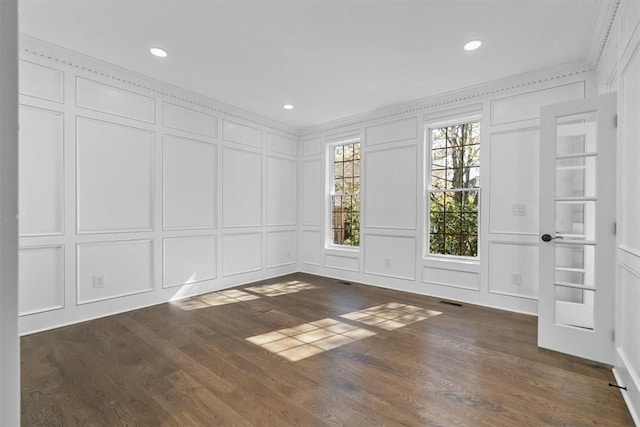 unfurnished room featuring recessed lighting, crown molding, a decorative wall, and dark wood finished floors