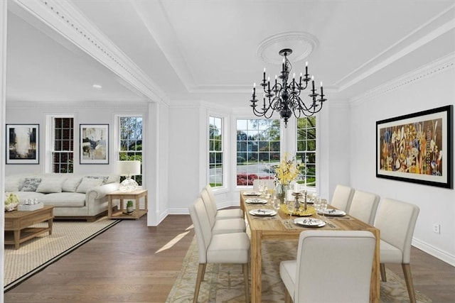 dining space with a raised ceiling, baseboards, wood finished floors, and a chandelier