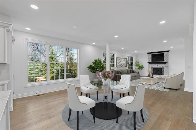 dining room featuring visible vents, a fireplace, baseboards, light wood finished floors, and recessed lighting