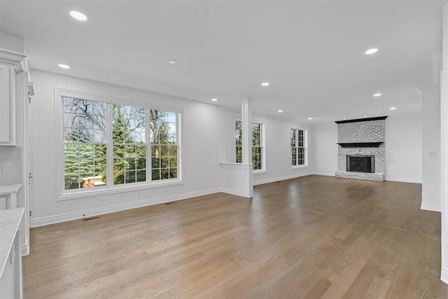 unfurnished living room featuring visible vents, a brick fireplace, baseboards, recessed lighting, and light wood-style flooring