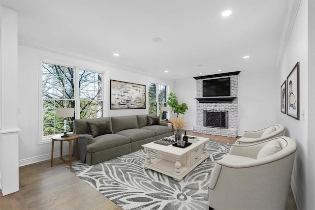 living area featuring a brick fireplace, recessed lighting, ornamental molding, and wood finished floors