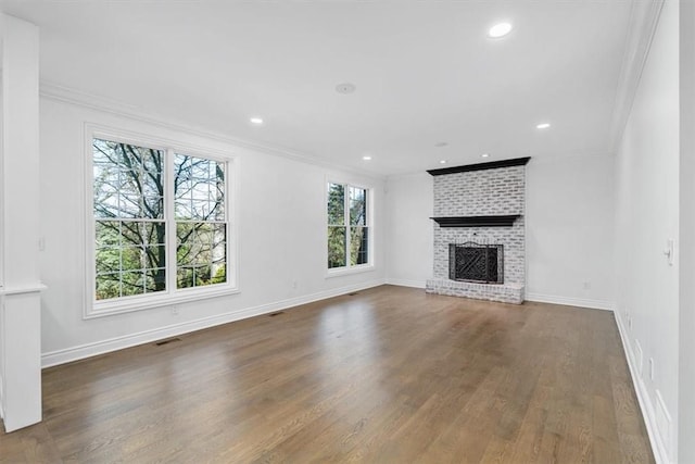 unfurnished living room with baseboards, ornamental molding, wood finished floors, and a fireplace