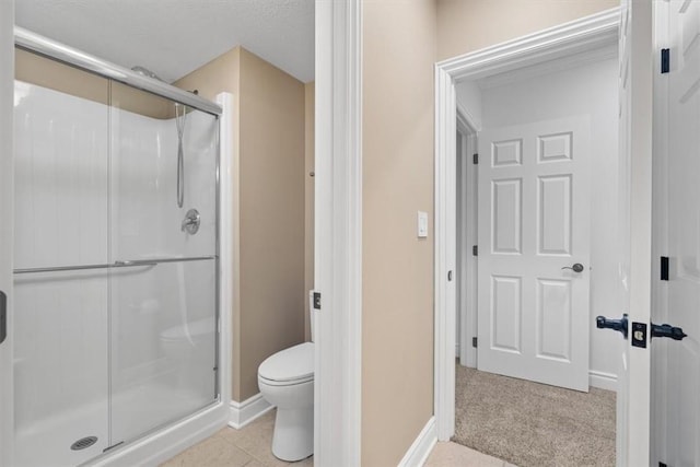 bathroom featuring toilet, baseboards, and a shower stall
