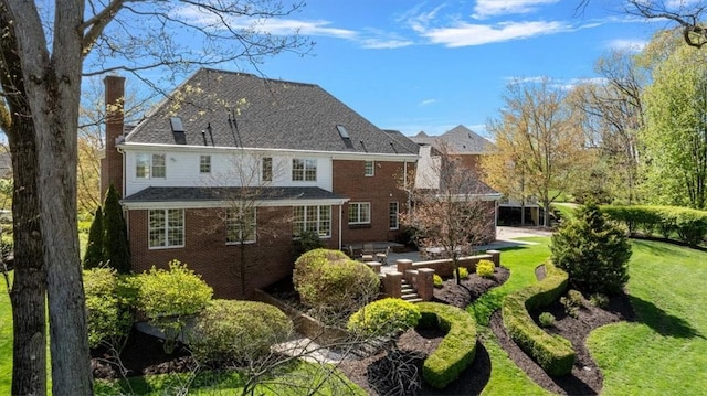 rear view of house with a patio, a chimney, a yard, and brick siding