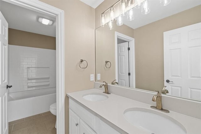 bathroom with double vanity, a sink, tile patterned floors, and toilet