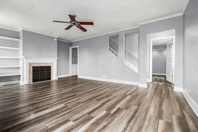 unfurnished living room with built in features, a ceiling fan, wood finished floors, a tile fireplace, and baseboards
