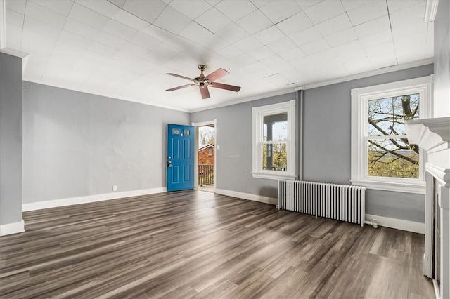 spare room featuring wood finished floors, radiator heating unit, ceiling fan, and a wealth of natural light
