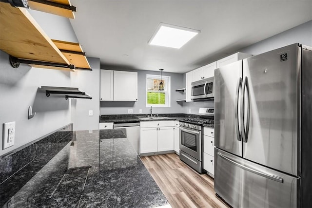 kitchen featuring light wood-style floors, open shelves, white cabinetry, appliances with stainless steel finishes, and a sink
