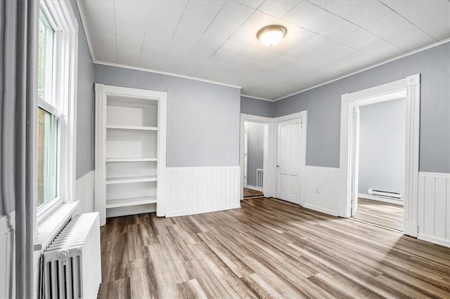unfurnished bedroom with ornamental molding, a baseboard radiator, radiator heating unit, and multiple windows